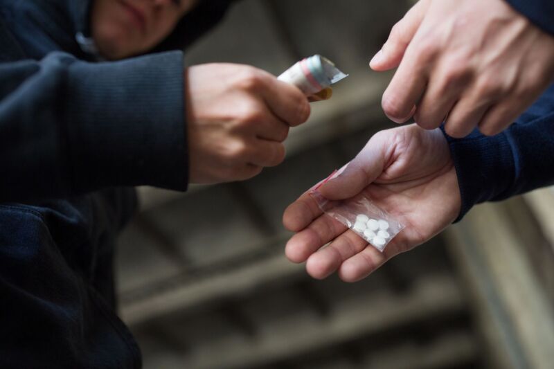 A person exchanging drugs for money.