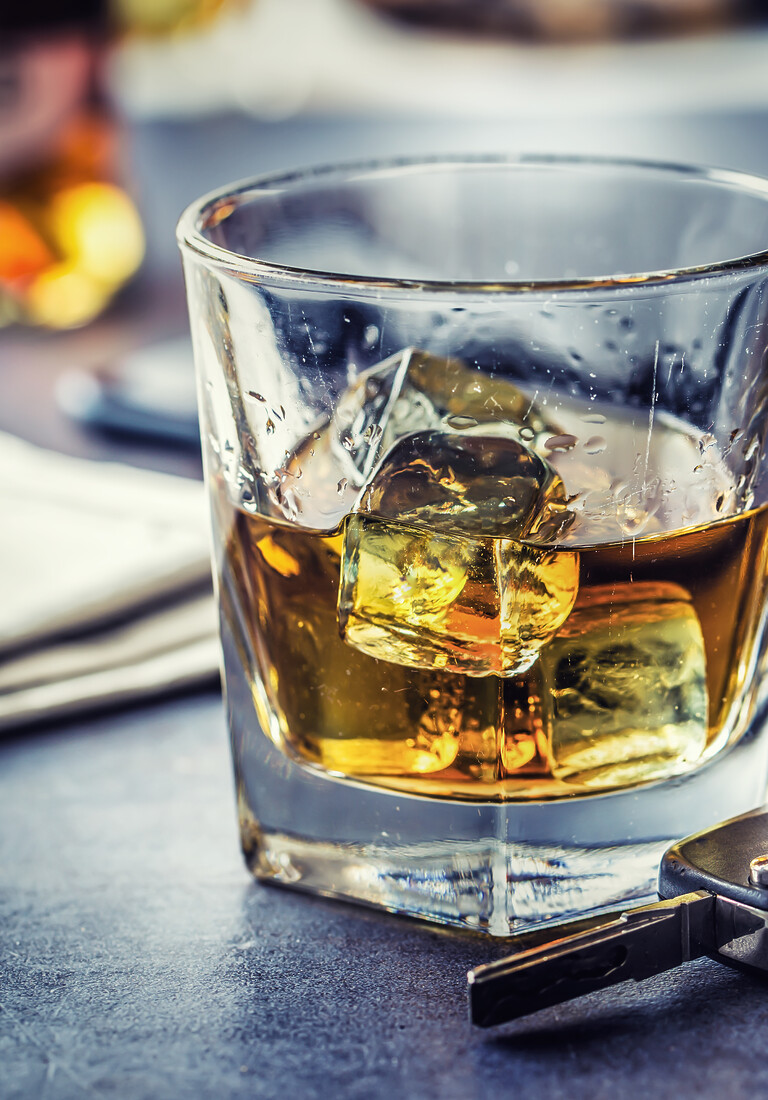 Car keys and glass of alcohol on table in pub or restaurant.