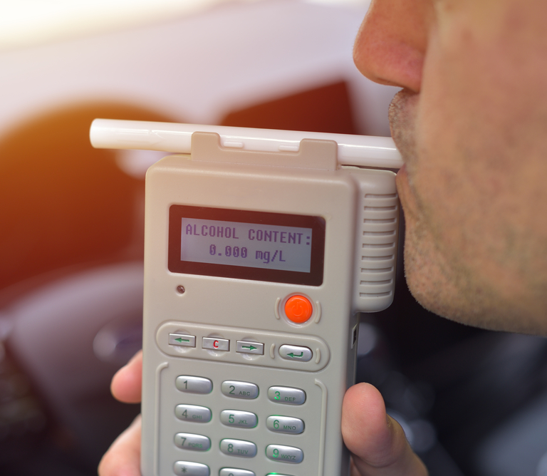 A man blowing into a breathalyzer device during a DUI stop.