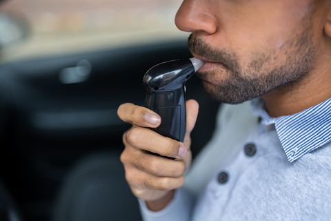 A man blowing into a DUI breathalyzer device.