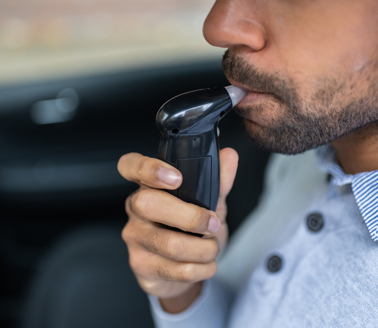A man blowing into a DUI breathalyzer device.