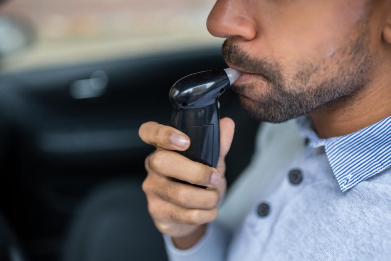 A man blowing into a DUI breathalyzer device.