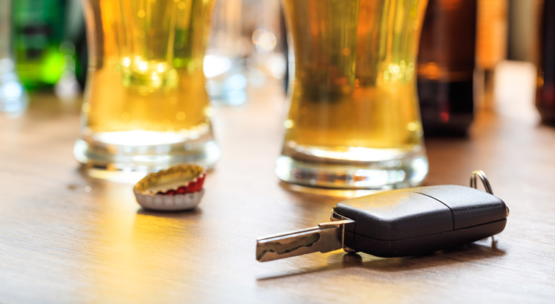 Glasses of beer on a table next to a car key.