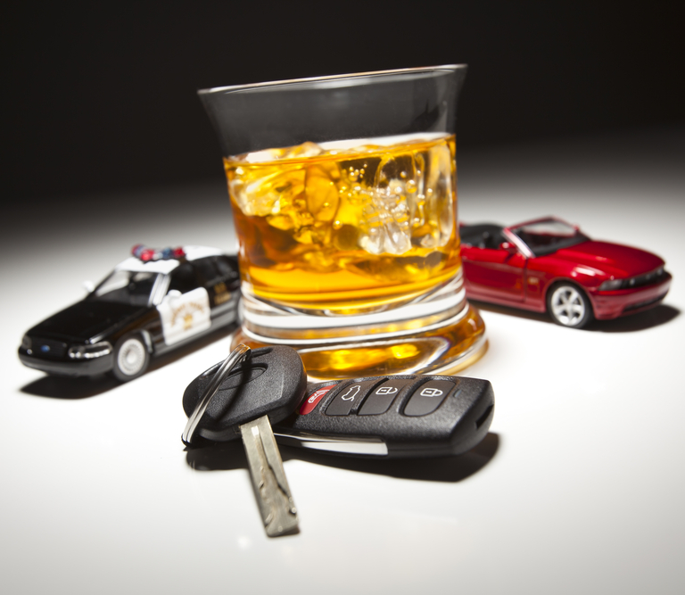 An image of a car keys, and an alcoholic drink, with a cop car and red car sitting next to it.