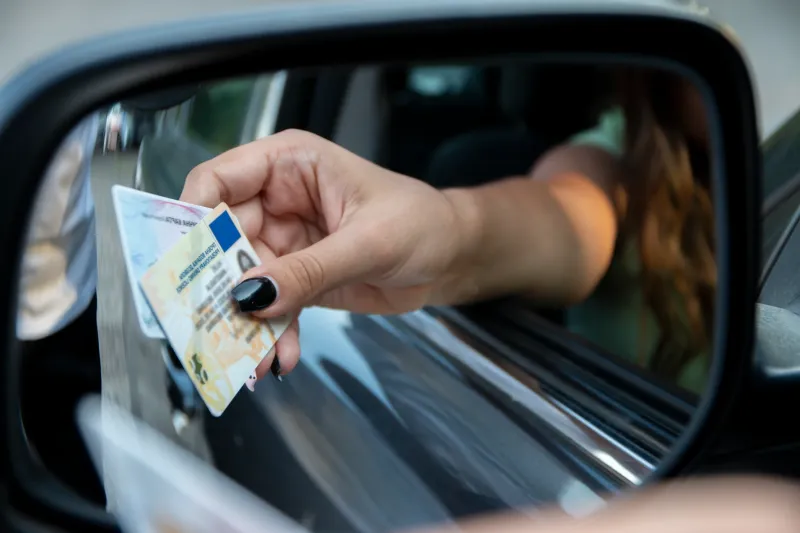 Driver’s license being handed over during a DUI stop, representing whether your license is immediately lost after a DUI arrest in Kansas.